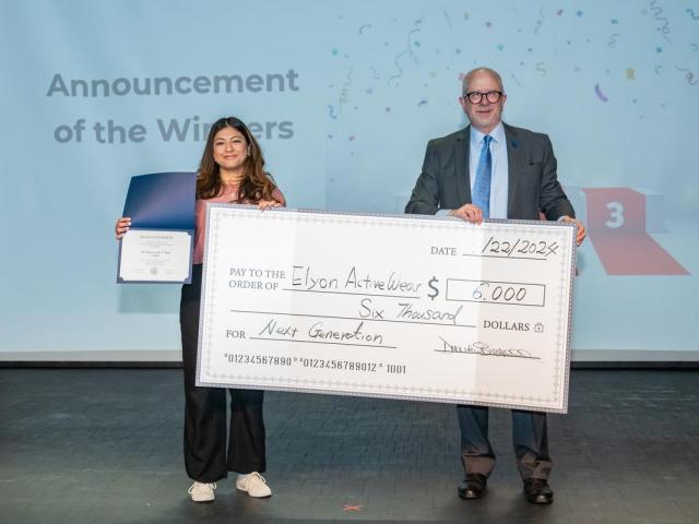 The winner of the Business Plan Competition, Joceline Guerra, stands with Kean's provost holding a big check for $6,000. 
